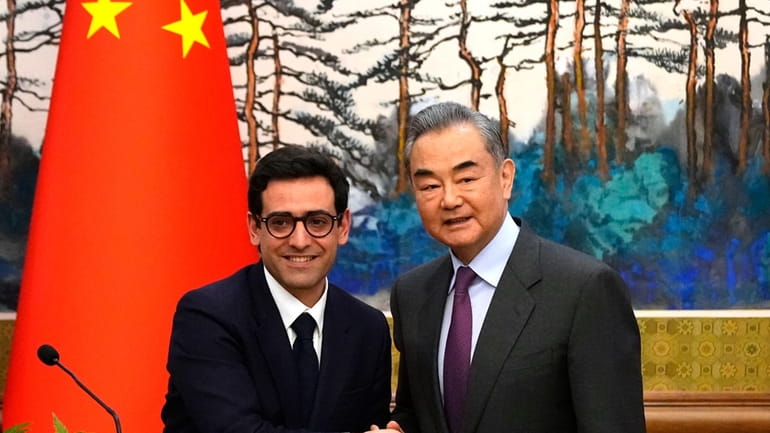 Chinese Foreign Minister Wang Yi, right, shakes hands with French...