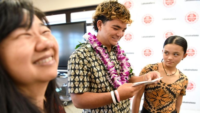 Lahainaluna High School 2024 graduate Talan Toshikiyo, center, stands by...