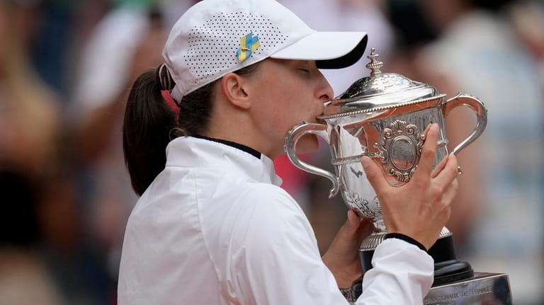 Poland's Iga Swiatek kisses the trophy as she celebrates winning...
