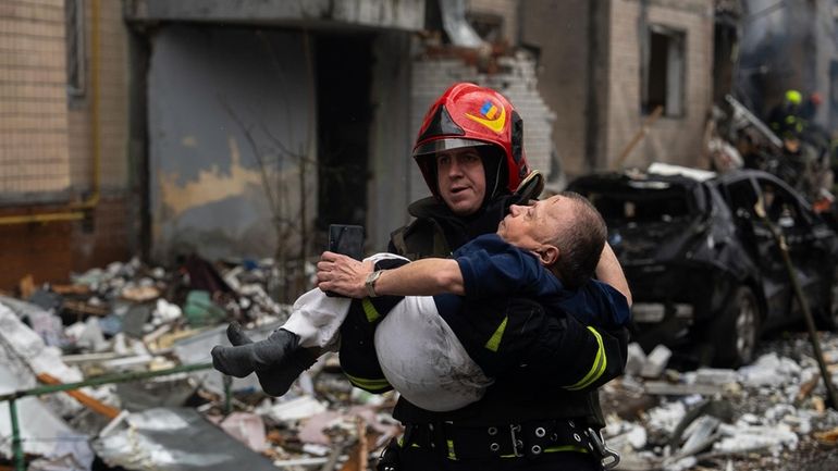 A firefighter carries a man from a damaged residential building...