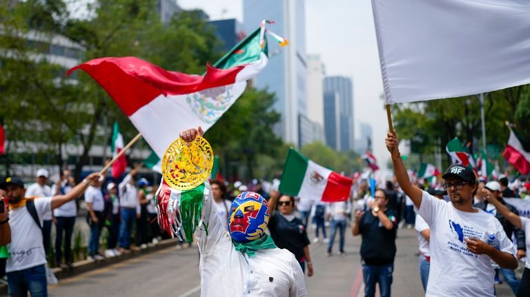 Judicial workers, one wearing a "lucha libre" wrestling mask, protest...