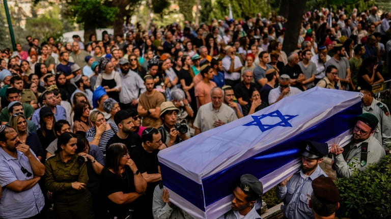 Israeli soldiers carry the flag-covered coffin of fallen soldier Shilo Rauchberger...