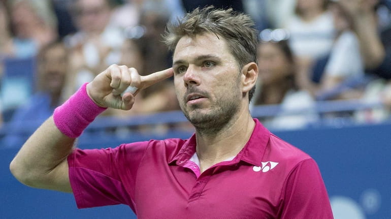 Stan Wawrinka reacts by pointing to his head after winning...