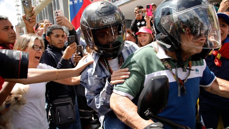 Opposition leader Maria Corina Machado is driven away on a...