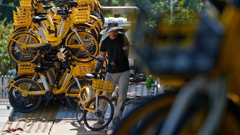 A worker loads shared bikes from a truck on a...