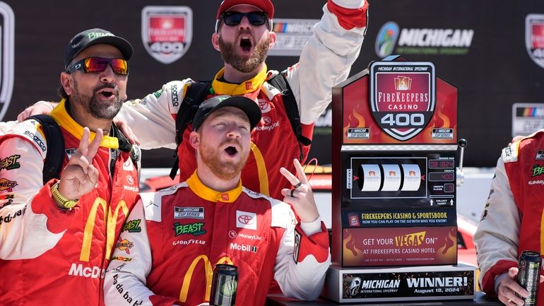 Tyler Reddick and crew stand by the winner's trophy after...