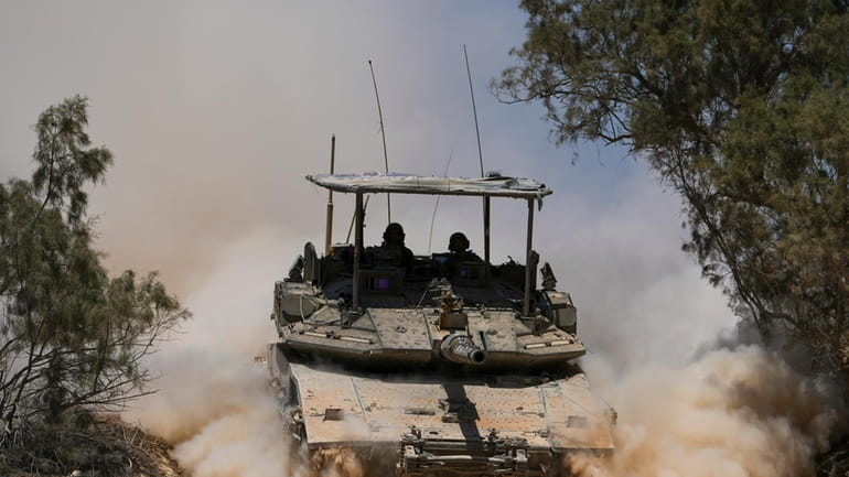 Israeli soldiers drive a tank near the Israeli-Gaza border, in...