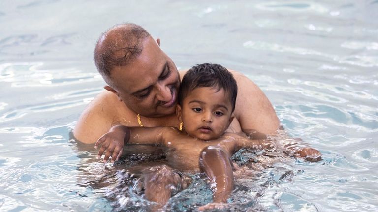 Rates Ali Hamid helps his 1-year-old son, Abdul, during swimming...