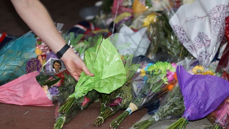 A fan leaves flowers at a memorial set up for...