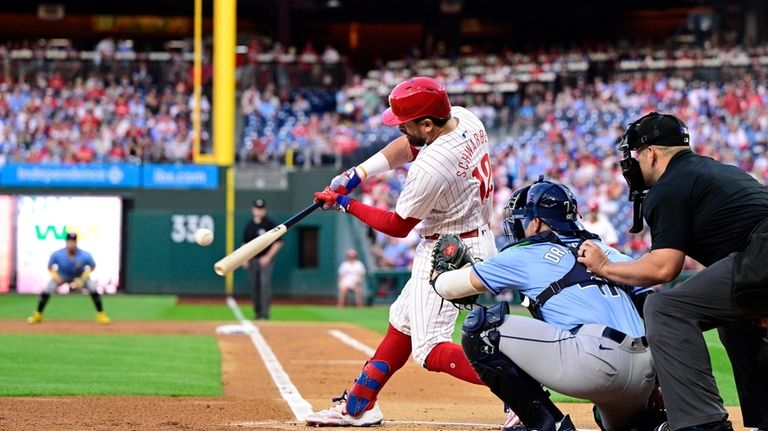 Philadelphia Phillies' Kyle Schwarber, center, hits a solo home run...