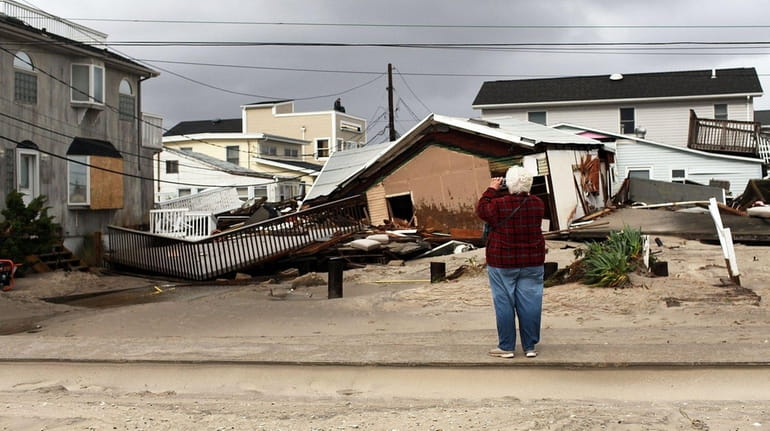 A woman photographs damage after Hurricane Sandy on Oct. 30,...
