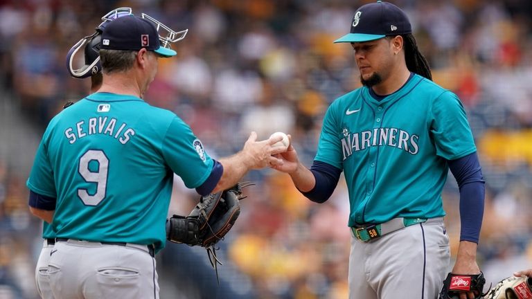 Seattle Mariners starting pitcher Luis Castillo, right, hands the ball...