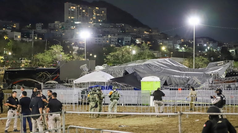 Security forces stand around a stage that collapsed due to...