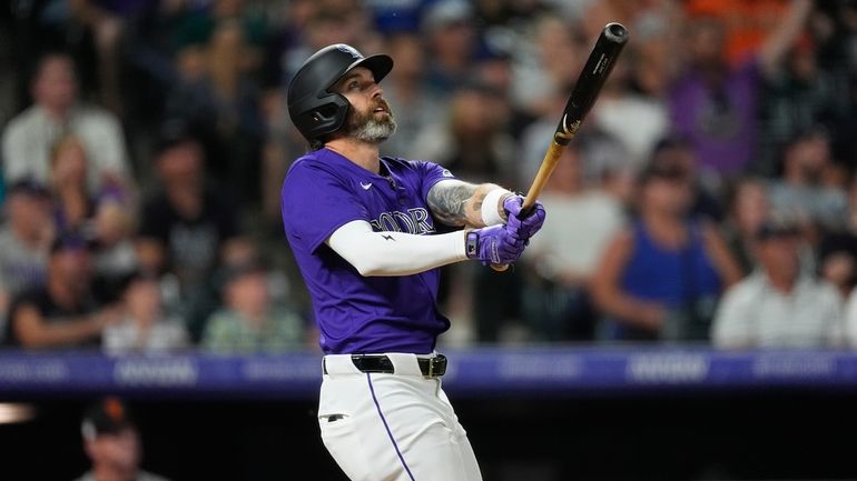 Colorado Rockies' Jake Cave follows the flight of his three-run...