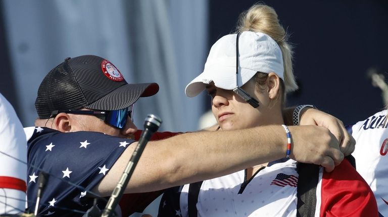 Archer Tracy Otto from the U.S., right, is assisted by...