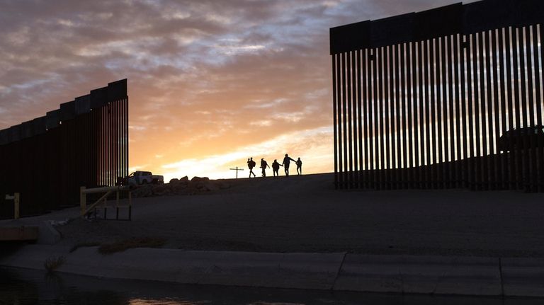 A pair of migrant families from Brazil passes through a...