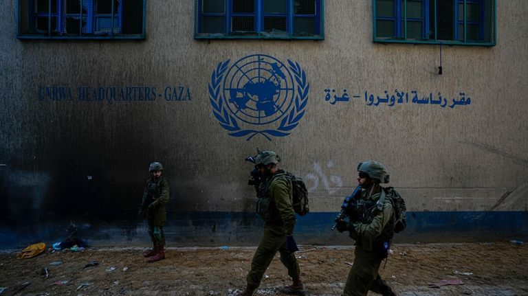 Israeli soldiers take position as they enter the UNRWA headquarter...