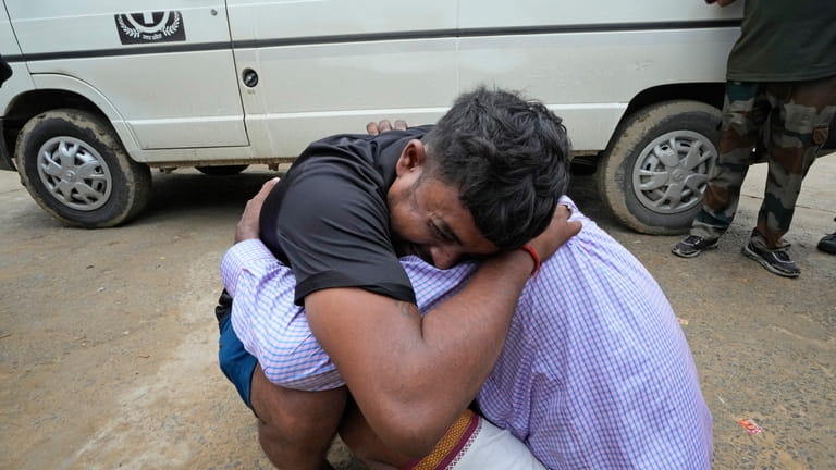 A man weeps while hugging the father-in-law of his 37-year-old...