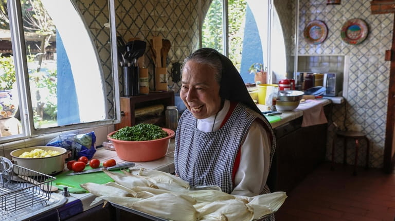 Nun Maria Ines Maldonado, 76, carries a tray of corn...