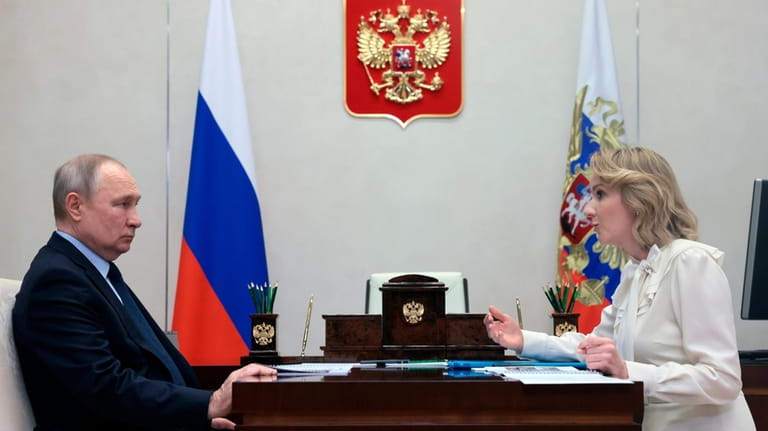 Russian President Vladimir Putin, left, listens to Russian Presidential Commissioner...