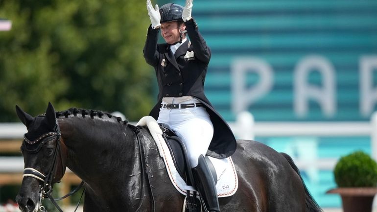 Germany's Isabell Werth riding Wendy applauds during the dressage team...