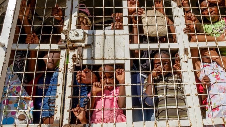 Haitians detained for deportation stand in a police truck on...