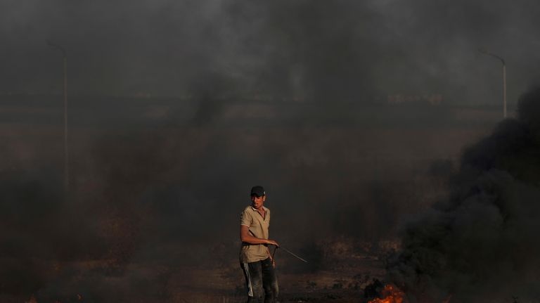 A Palestinian protester burns tires during clashes with Israeli security...