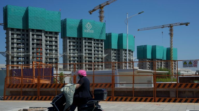 A women rides her bike past a housing project under...