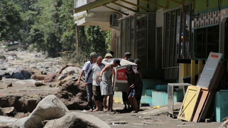 People carry a refrigerator at a village affected by a...