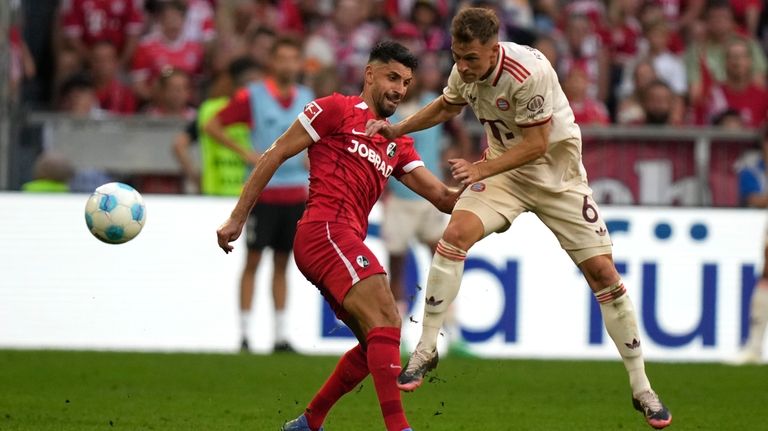 Freiburg's Vincenzo Grifo, left, and Bayern's Joshua Kimmich fight for...