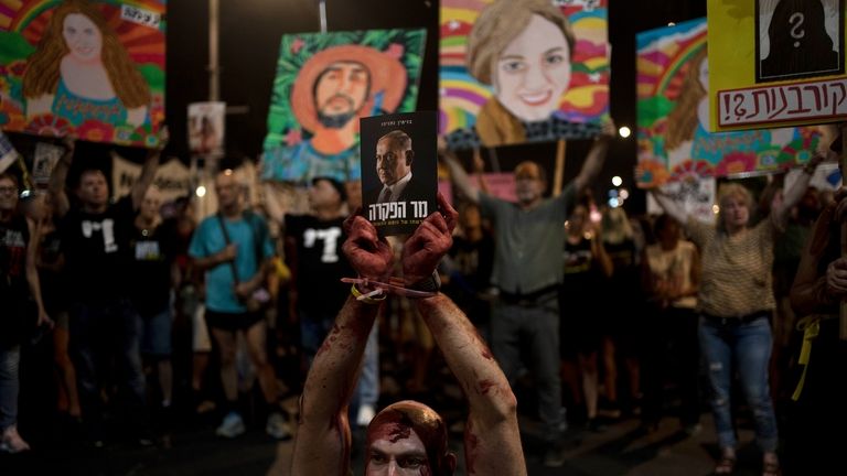 An activist wears theatrical blood, bound wrists and his mouth...