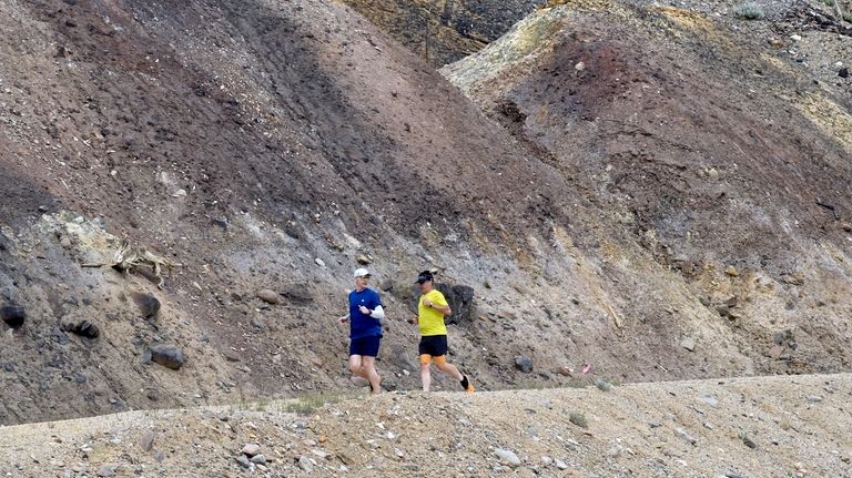 Runners pass by piles of ore discarded decades ago in...