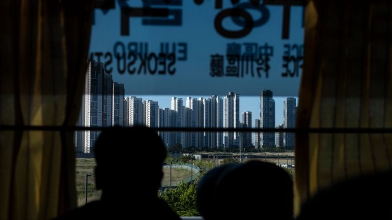 A tourist views high-rise apartment buildings from a bus in...