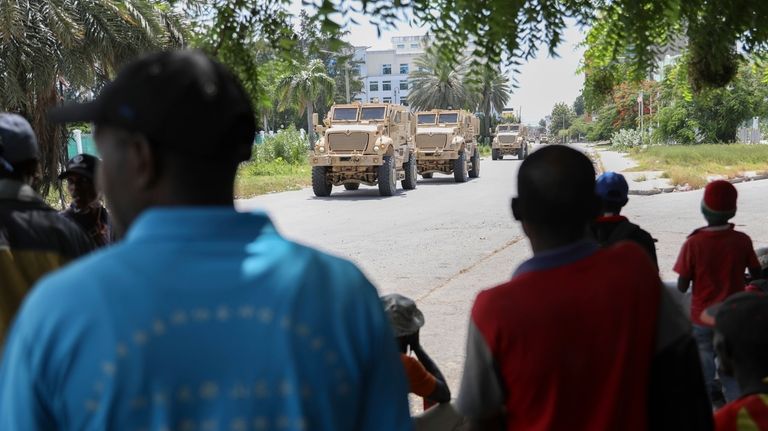 Residents look at armored vehicles carrying Kenyan police officers who...