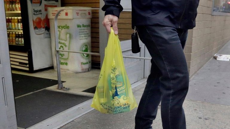 A man carries his purchase in a plastic bag from...