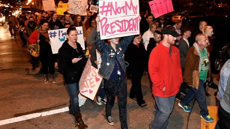 Protesters holds up signs in opposition of Donald Trump's presidential...