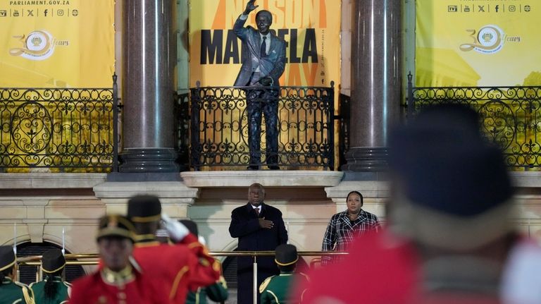 South African President Cyril Ramaphosa, beneath a statue of former...