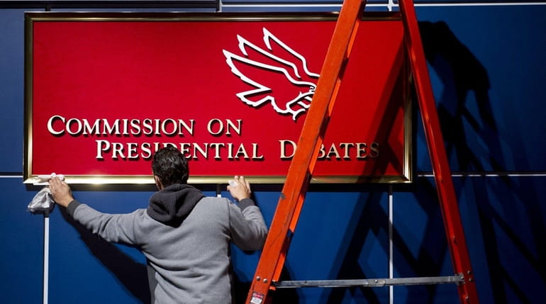 A worker cleans a sign for the Commission on Presidential...
