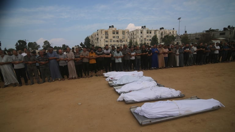 Mourners pray by the bodies of al-Agha family members who...