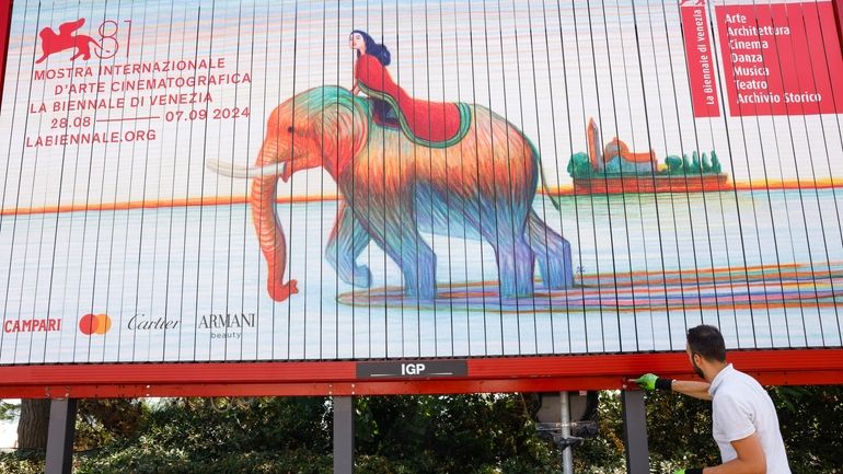 Workers paint signage for the 81st edition of the Venice...