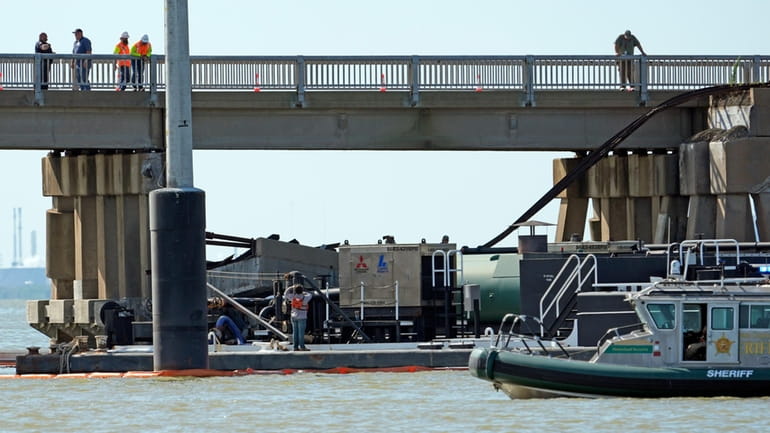 Workers survey the site where a barge crashed into the...
