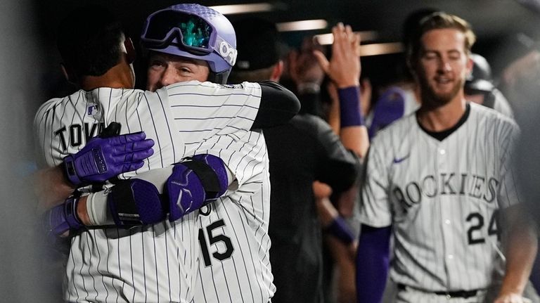 Colorado Rockies' Ezequiel Tovar, left, hugs Hunter Goodman (15) who...