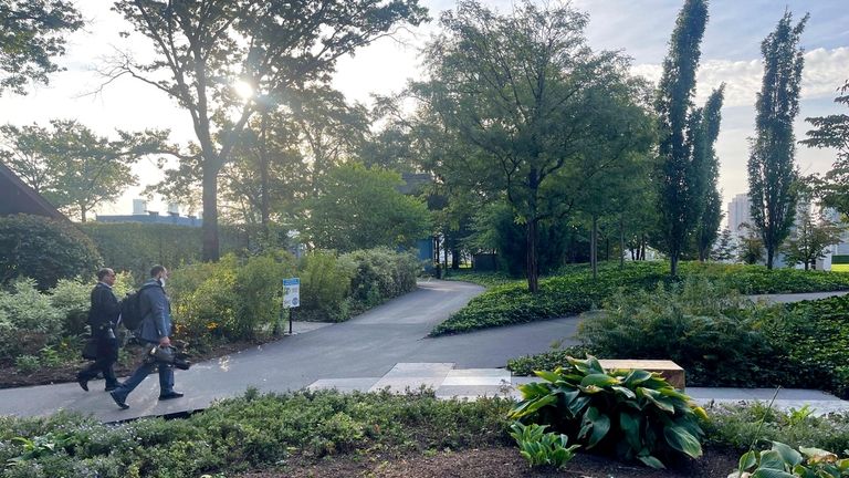 Two journalists walk through a park area on the north...