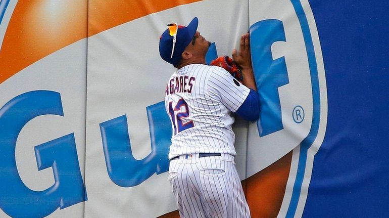 Juan Lagares collides with the wall after making a catch...