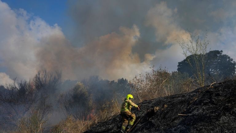 A firefighter works in the area around a fire after...