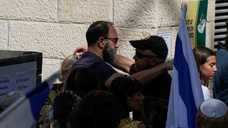 A mourner comforts Jon Polin, left, father of Israeli-American hostage...