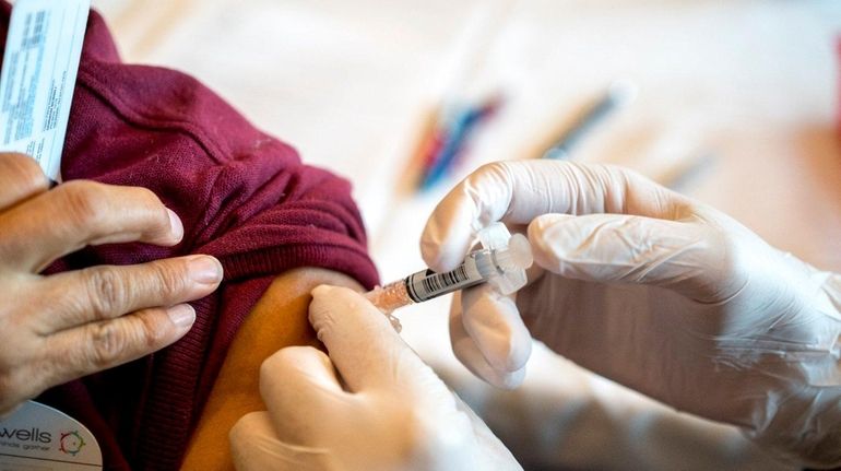 Pharmacist Gregory Lachhman administers a flu shot during a free...