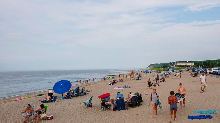 People hang on the beach after hours at Cedar Beach...