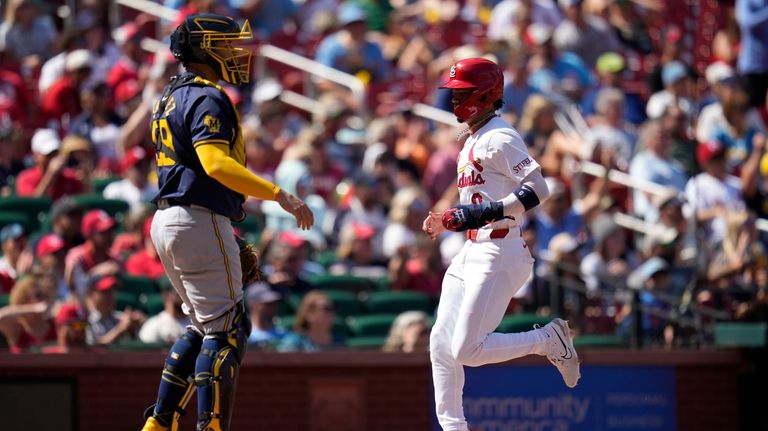 St. Louis Cardinals' Masyn Winn, right, scores past Milwaukee Brewers...