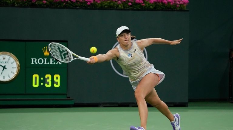 Iga Swiatek, of Poland, returns a shot to Elena Rybakina,...